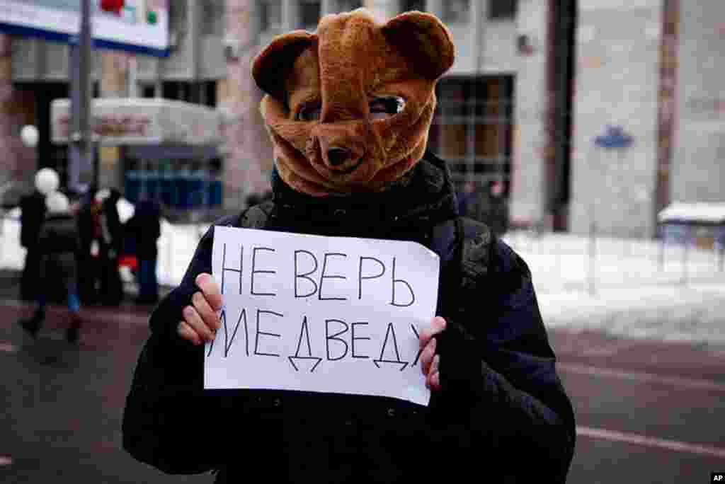 A protester wearing a bear mask at the rally with a sign that reads "Don't believe the bear" -- President Dmitri Medvedev's last name in Russian means bear, December 24, 2011. (VOA - Y. Weeks)