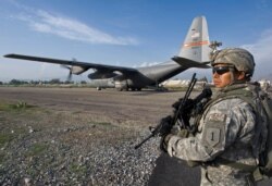 FILE - A member of the ISAF Security Forces secures the perimeter of a USAF C-130 cargo plane in Jalalabad, Sept. 17, 2008.