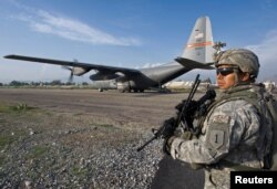 FILE - A member of the ISAF Security Forces secures the perimeter of a USAF C-130 cargo plane in Jalalabad, Sept. 17, 2008.