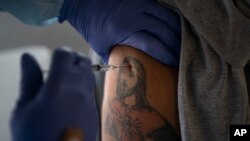 El trabajador agrícola Jorge Americano recibe la vacuna de Pfizer-BioNTech en su brazo tatuado en Mecca, California, el 21 de enero de 2021. [Foto: AP]