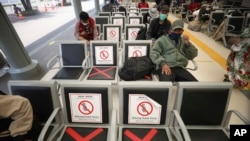 Men sit spaced apart as a social distancing effort to help curb the spread of the coronavirus in a train station waiting area, April 7, 2020, in Jakarta, Indonesia. 