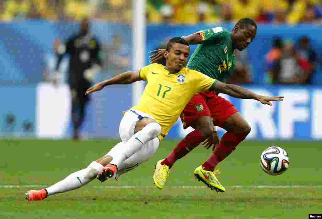 Pemain Brazil Luiz Gustavo memperebutkan bola dengan pemain Kamerun Enoh Eyong dalam pertandingan di Stadion Nasional Brasilia di Brasilia, 23 Juni 2014.