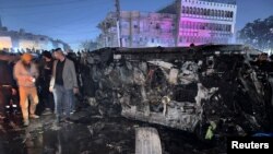 La gente inspecciona un vehículo después de lo que fuentes de seguridad dijeron que fue un ataque mortal con aviones no tripulados, en Bagdad, Irak, el 7 de febrero de 2024.