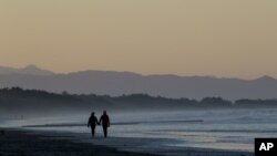 FILE - A couple walk along New Brighton Beach in Christchurch, New Zealand, June 9, 2020. Then-Health Minister David Clark was heavily criticized for ignoring lockdown and taking his family to a beach. He has since resigned.