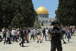 Seorang petugas polisi Israel berjaga-jaga ketika pria Yahudi mengunjungi Masjid Kubah Batu di kompleks Masjid Al Aqsa, selama ritual berkabung tahunan Tisha B'Av, di Kota Tua Yerusalem, 18 Juli 2021. (Foto: AP)