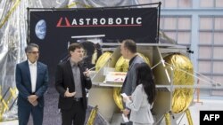 FILE - A NASA official speaks with an Astrobotic Technology executive about a lunar lander, at Goddard Space Flight Center in Maryland, in this May 31, 2019, handout photograph obtained courtesy of NASA.