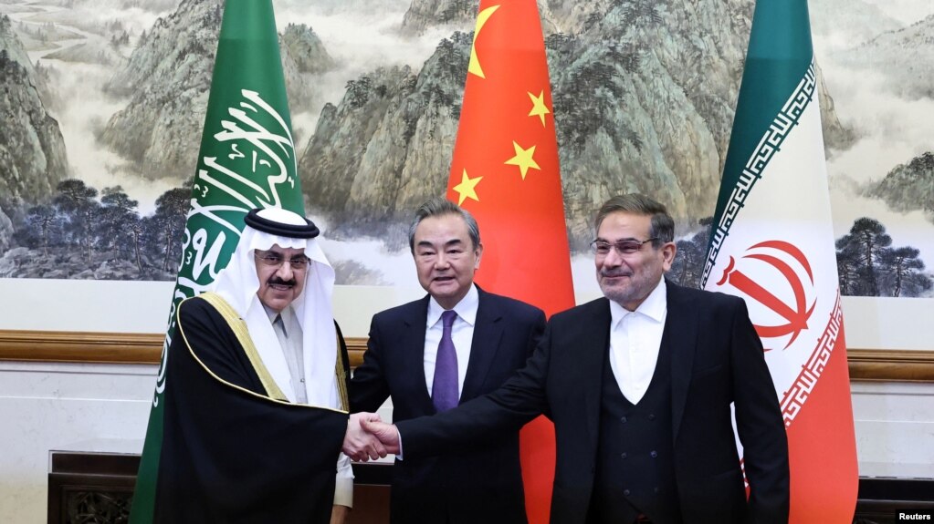 伊朗最高国家安全委员会秘书阿里·沙姆哈尼（右）在北京同沙特国务大臣、内阁成员和国家安全顾问穆萨伊德·本·穆罕默德·艾班握手，中间是中共中央外办主任王毅。（2023年3月10日）(photo:VOA)