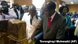FILE: Zimbabwe's President Robert Mugabe cuts his birthday cake as he marks his 93rd birthday at his offices in Harare, Tuesday, Feb. 21, 2017. Mugabe described his wife Grace, an increasingly political figure, as "fireworks" in an interview marking his 93rd birthday. (AP Photo/Tsvangirayi Mukwazhi)