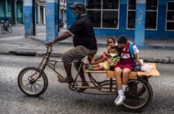 Un hombre transporta a sus hijos en un triciclo en La Habana, Cuba, el viernes 8 de enero de 2021, en medio de la pandemia del nuevo coronavirus.
