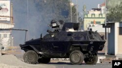 A police armored vehicle splattered with paint bombs fires tear gas toward Bahraini anti-government protesters during clashes in Sitra, Bahrain, Feb. 14, 2016. 