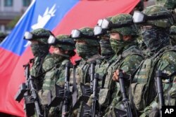 Para prajurit Taiwan berfoto di depan bendera Taiwan usai latihan bersama untuk mencegah gangguan militer China menjelang Tahun Baru China di Kota Kaohsiung, Taiwan, 11 Januari 2023. (Foto: Daniel Ceng/AP Photo)