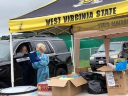 Parents and students arrive in their vehicles for health screenings and temperature checks before moving into residence halls at West Virginia State University campus, July 31, 2020, in Institute, West Virginia.