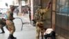 Soldiers beat a supporter of the opposition Movement for Democratic Change party of Nelson Chamisa outside the party's headquarters as they await the results of the general elections in Harare, Zimbabwe, Aug. 1, 2018.