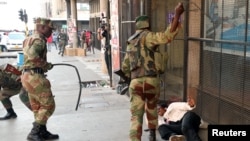 Soldiers beat a supporter of the opposition Movement for Democratic Change party of Nelson Chamisa outside the party's headquarters as they await the results of the general elections in Harare, Zimbabwe, Aug. 1, 2018.