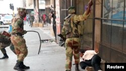 FILE: Soldiers beat a supporter of the opposition Movement for Democratic Change party of Nelson Chamisa outside the party's headquarters as they await the results of the general elections in Harare, Zimbabwe, Aug. 1, 2018.