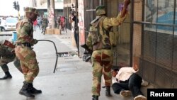 Soldiers beat a supporter of the opposition Movement for Democratic Change party of Nelson Chamisa outside the party's headquarters as they await the results of the general elections in Harare, Zimbabwe, Aug. 1, 2018.