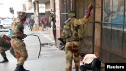 FILE: Soldiers beat a supporter of the opposition Movement for Democratic Change party of Nelson Chamisa outside the party's headquarters as they await the results of the general elections in Harare, Zimbabwe, Aug. 1, 2018.