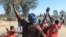 FILE: A rioter wearing a police helmet taken from a police officer joins angry protestors in Harare, Monday, July, 4, 2016.