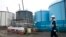 FILE - An employee walks past storage tanks for contaminated water at the tsunami-crippled Fukushima Daiichi nuclear power plant of the Tokyo Electric Power Co. in Okuma, Japan, Feb. 23, 2017.