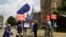 FILE - Anti-Brexit, EU supporters hold placards and European Union flags on Abingdon Green, backdropped by the Houses of Parliament in London, July 9, 2018.