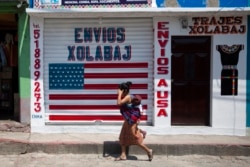 In this April 3, 2020 photo, a closed business featuring a U.S. flag and the Spanish phrase: "Send to U.S.A" in the largely indigenous town of Joyabaj, Guatemala, where half of the residents depend on remittances, almost all from the United States.