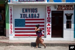 In this April 3, 2020 photo, a closed business featuring a U.S. flag and the Spanish phrase: "Send to U.S.A" in the largely indigenous town of Joyabaj, Guatemala, where half of the residents depend on remittances, almost all from the United States.