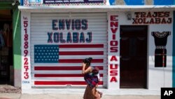 FILE - A closed business featuring a U.S. flag and the Spanish phrase "Send to U.S.A" is pictured in the largely indigenous town of Joyabaj, Guatemala, where half of the residents depend on remittances, almost all from the United States, April 3, 2020.