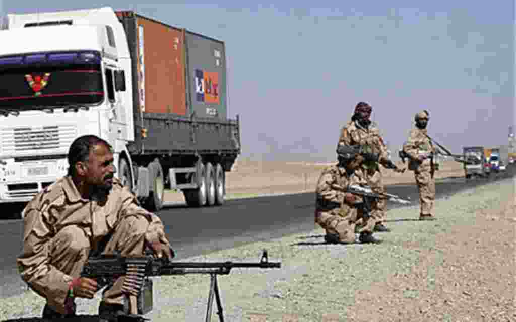 Private security contractors guard a part of a route as NATO supply trucks drive past in the province of Ghazni, south-west of Kabul, Afghanistan, 27 Oct 2010.