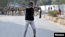 Seorang pria tak dikenal mengacungkan pistol selama protes terhadap undang-undang kewarganegaraan baru, di luar Universitas Jamia Millia Islamia di New Delhi, India, sebagai ilustrasi. (Foto: Reuters)