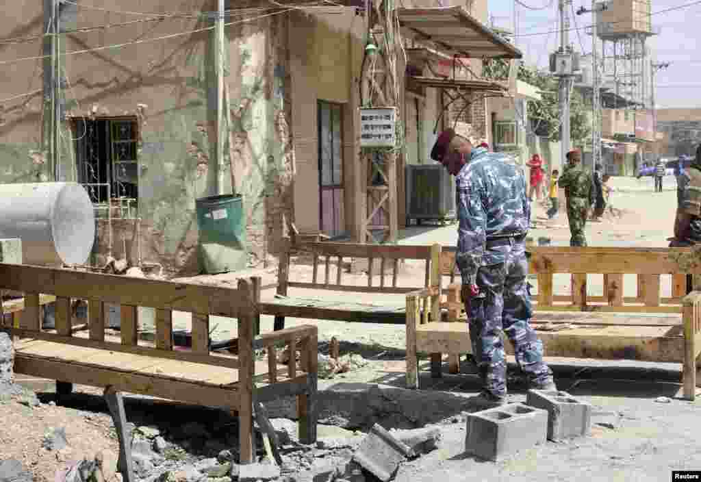 An Iraqi policeman inspects the site of a suicide bombing attack at a coffee shop in the Shi'ite district of the city of Baquba, about 50 kilometers northeast of Baghdad, July 2, 2013.