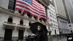 A man wearing a mask walks by the New York Stock Exchange, March 17, 2020. 