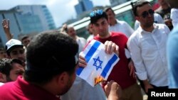 Un Palestinien tient un drapeau d'Israël dans ses mains, à Gaza, le 18 juillet 2014.