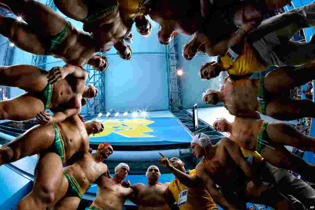 Australia&#39;s coach John Fox, pointing finger at bottom center right, talks to his players before a men&#39;s quarterfinal water polo match against Serbia.