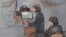 In this courtroom sketch, defense attorney Judy Clarke is depicted addressing the jury as defendant Dzhokhar Tsarnaev, right, sits during closing arguments in Tsarnaev's federal death penalty trial, April 6, 2015, in Boston. 
