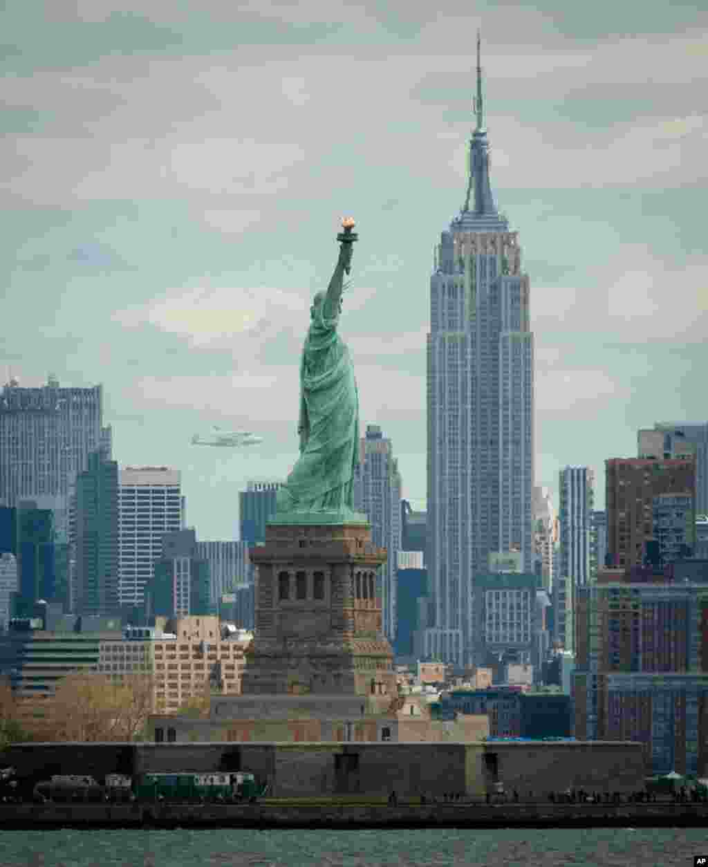 Space shuttle Enterprise, mounted atop a NASA 747 Shuttle Carrier Aircraft, is seen off in the distance behind the Statue of Liberty, April 27, 2012, in New York. Enterprise was the first shuttle orbiter built for NASA performing test flights in the atmos