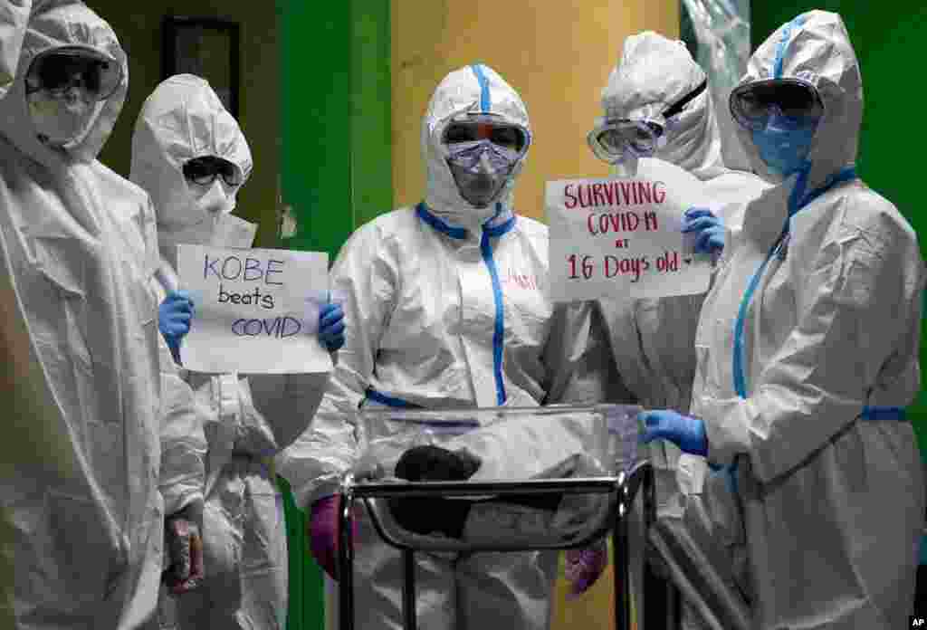 Health workers wearing protective suits holds signs about a 16-day-old infant who has recovered from COVID-19 and is being discharged from the National Children&#39;s Hospital in Quezon city, Metro Manila, Philippines.