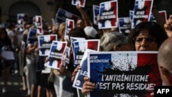 Manifestantes seguram cartazes com as frases "O antissemitismo não é residual" enquanto se reúnem para condenar a alegada violação antissemita de uma menina de 12 anos, durante uma manifestação na praça Lyon Terreaux, em Lyon, no centro-leste de França, a 19 de junho de 2024.