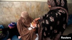 Seorang petugas tengah memberikan vaksinasi polio untuk seorang anak di sebuah rumah sakit di Peshawar (19/12). Seorang petugas dilaporkan tewas terbunuh saat memberikan vaksinasi di Jamrud, wilayah kesukuan Khuber, Sabtu pagi (21/12).