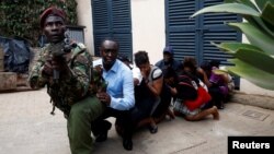 People are evacuated by a member of security forces at the scene where explosions and gunshots were heard at the Dusit hotel compound, in Nairobi, Kenya, Jan. 15, 2019.