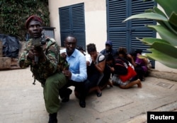 People are evacuated by a member of security forces at the scene where explosions and gunshots were heard at the Dusit hotel compound, in Nairobi, Kenya, Jan. 15, 2019.