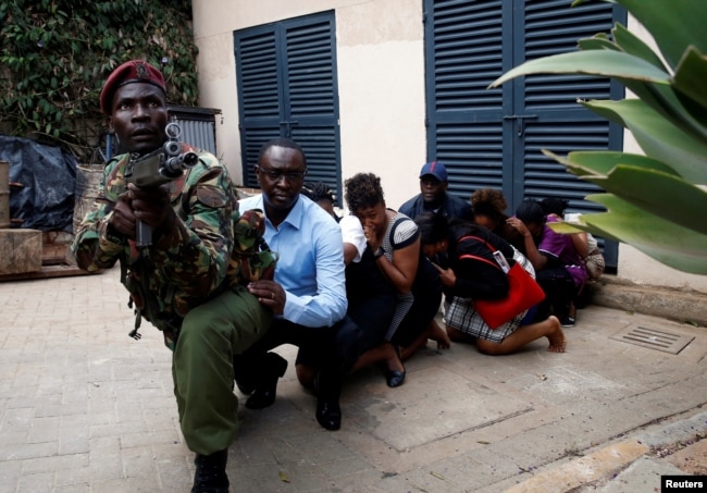 People are evacuated by a member of security forces at the scene where explosions and gunshots were heard at the Dusit hotel compound, in Nairobi, Kenya, Jan. 15, 2019.