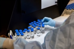 FILE - A lab technician inspects filled vials of remdesivir at a Gilead Sciences facility in La Verne, Calif., March 11, 2020.