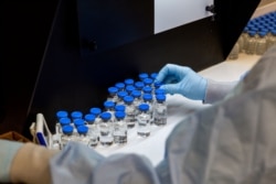 A lab technician inspects filled vials of remdesivir at a Gilead Sciences facility in La Verne, California, March 11, 2020.