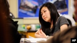 FILE - Sally Kim takes notes during a physics class at Columbia Independent School in Columbia, Mo. Kim's parents, who live in South Korea, sent her to live with relatives in Columbia for a better education that provides more collegiate opportunities.