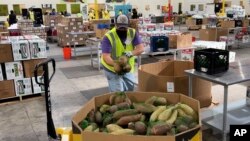 Seorang pekerja meletakkan kantong ubi jalar dalam sebuah wadah di gudang Bank Makanan Komunitas Alameda County di Oakland, California, 5 November 2021. Kantor Gubernur California memproyeksikan upah minimum akan naik menjadi $15,50 per jam mulai 1 Januari 2023. 