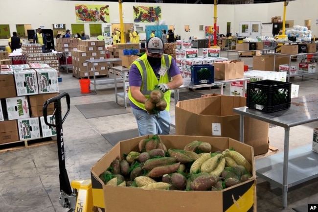 A worker puts bags of sweet potatoes in a container in the warehouse of the Alameda County Community Food Bank in Oakland, California, Nov. 5, 2021.