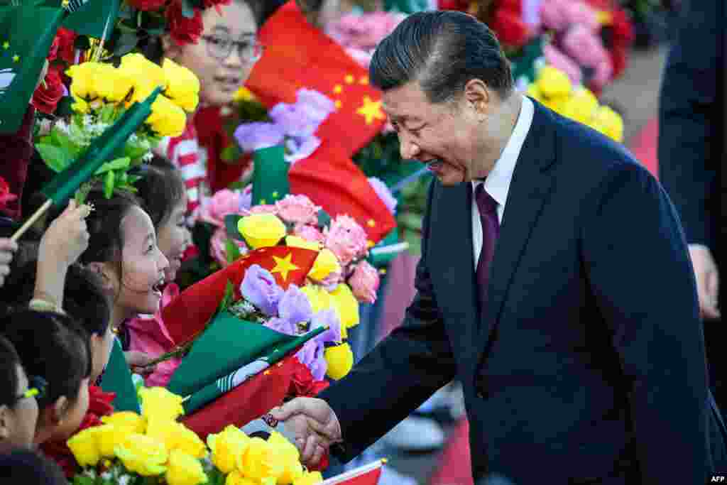 Chinese President Xi Jinping, right, shakes hands with a girl as she and other children welcome Xi following his arrival at Macau&#39;s international airport in Macau.