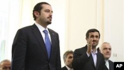 Iranian President Mahmoud Ahmadinejad, right, waves to the media, as he walks up the steps with Lebanese Prime Minister Saad Hariri, prior to their meeting at the Iranian Foreign Ministry, in Tehran, Nov. 28, 2010.