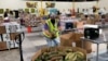 Seorang pekerja meletakkan kantong ubi jalar dalam wadah di gudang Bank Makanan Komunitas Alameda County di Oakland, California, 5 November 2021. (Foto: AP)