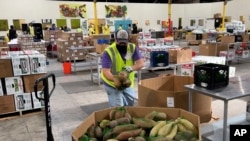 Seorang pekerja meletakkan kantong ubi jalar dalam wadah di gudang Bank Makanan Komunitas Alameda County di Oakland, California, 5 November 2021. (Foto: AP)